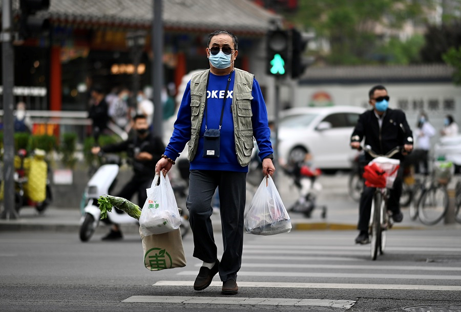 4月25日，北京市朝阳区小关街道，市民提着蔬菜过马路